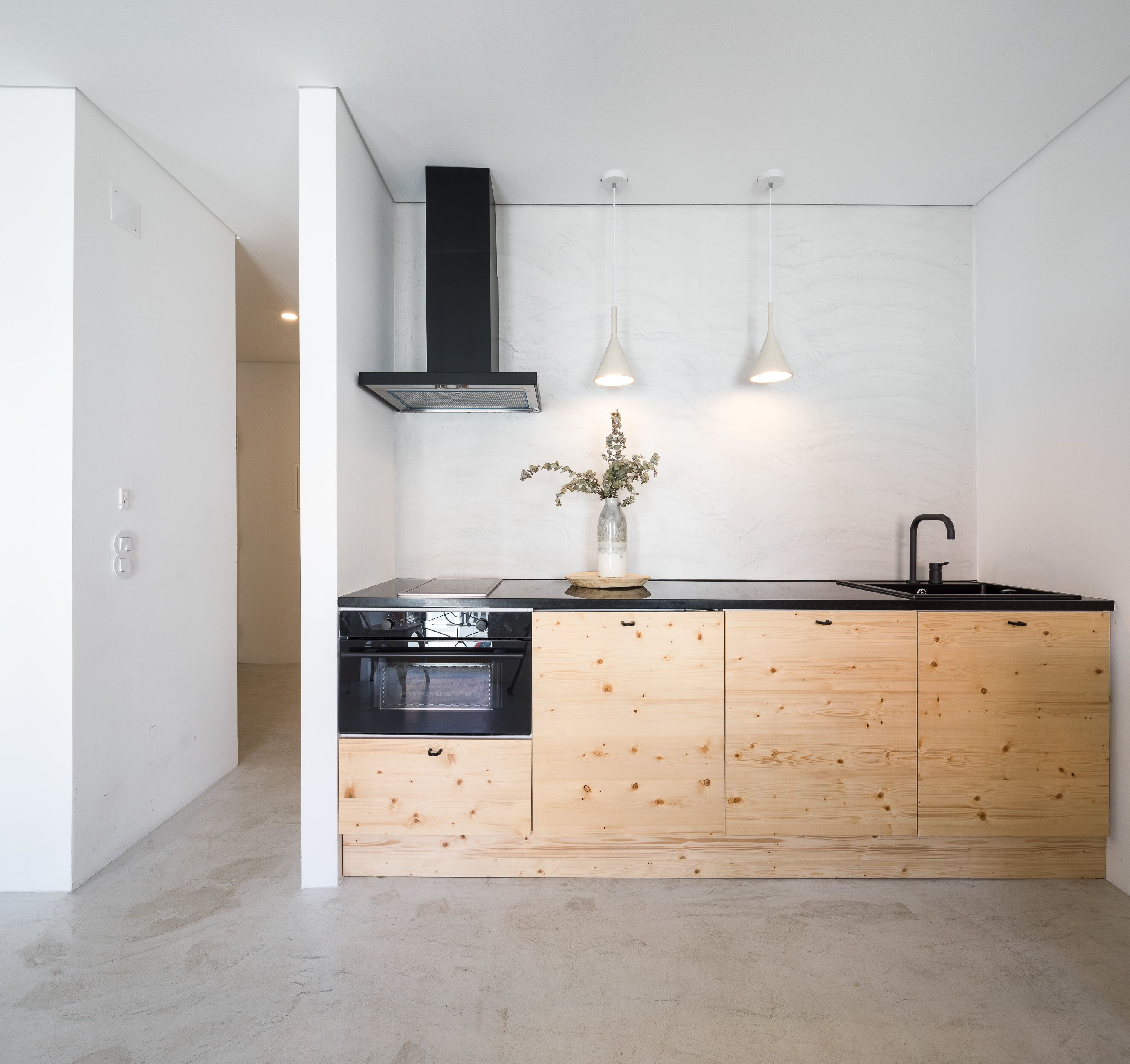 Une cuisine moderne avec un poêle noir, des armoires en bois et des luminaires suspendus.