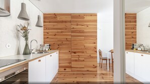 A modern kitchen with wooden panel walls, white cabinetry, and a dining area with a table and chairs.