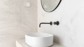 A bathroom with a white marble sink, a black faucet, and a round mirror.