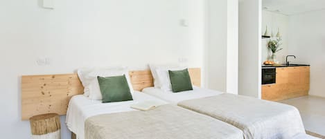 A modern bedroom with two beds, a wooden headboard, and a small bedside table.