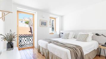 Quarto com cama, mesa de cabeceira, abajur e vista para o exterior.