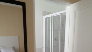 Une chambre avec un lit, une salle de bain avec un lavabo et un espace douche.