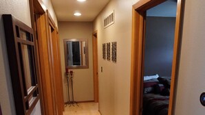 A narrow hallway with wooden doors, a ceiling light, and a bed visible in the adjacent room. - 5 Bedrooms and a Great Location (Sioux Falls)