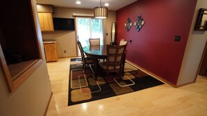 A dining area with a table and chairs, a patterned rug, and a red accent wall. - 5 Bedrooms and a Great Location (Sioux Falls)
