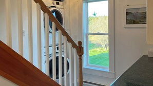 A staircase with wooden railings leading to a laundry room with a washing machine and dryer.