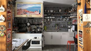 A cozy kitchen with a wooden interior, a coffee-themed sign, and various kitchen utensils and appliances. - Hostel Charme da Graça (Lisbon)