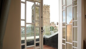 A room with a large window, a wooden floor, and a view of a castle. - Y Capel (Conwy)