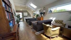 A spacious living room with a large bookshelf, a grey sofa, a beige armchair, and a wooden coffee table. - Y Capel (Conwy)