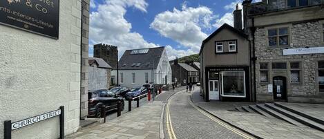 Una calle adoquinada con edificios a ambos lados, incluyendo un letrero que dice 'Wild Violet & Co' y 'J W Hughes & Co'.