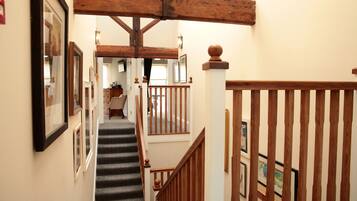 A staircase with wooden railings and a handrail, leading to an upper floor.