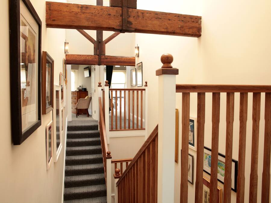 A staircase with wooden railings and a handrail, leading to an upper floor.
