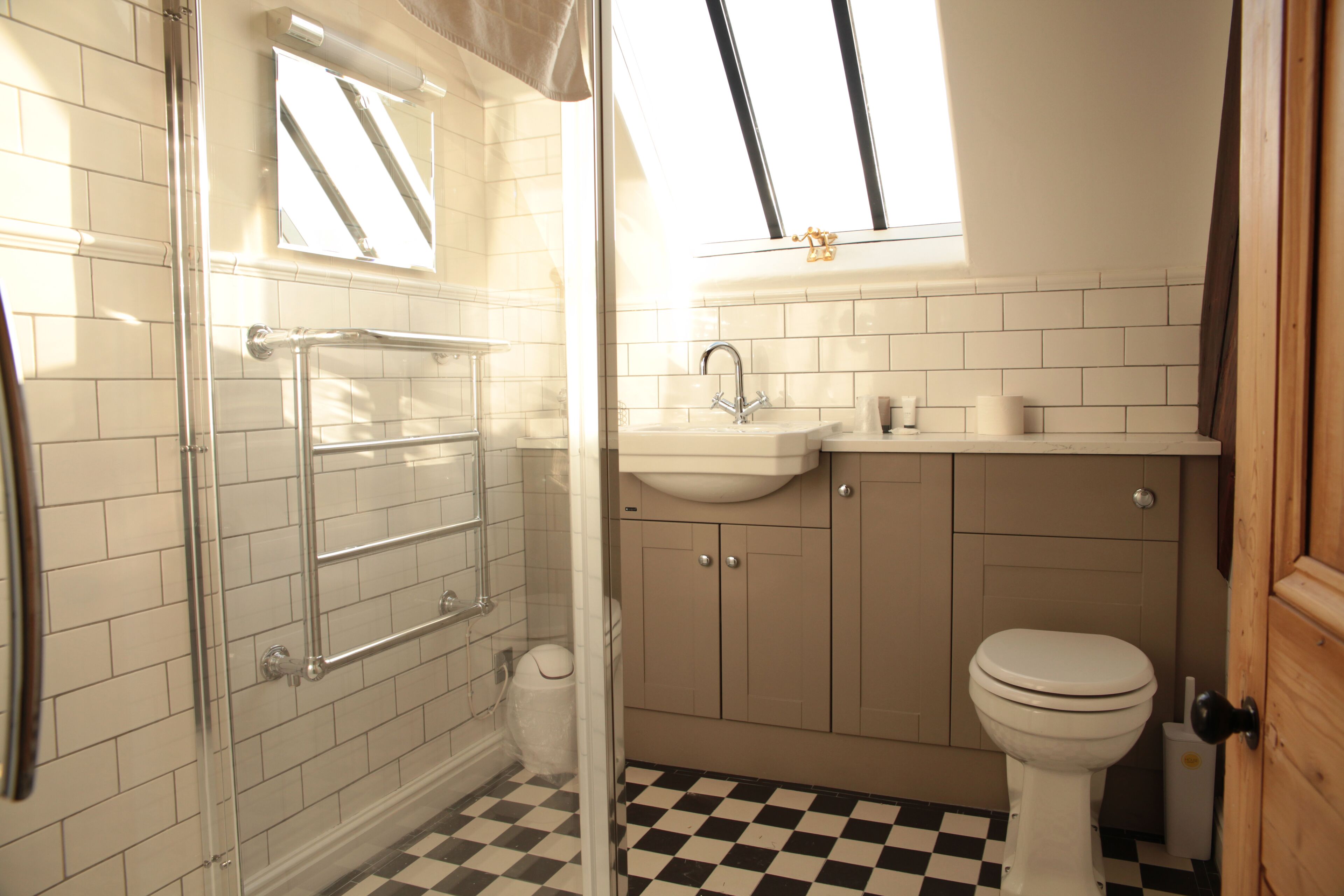 A bathroom with a checkered floor, a glass shower enclosure, a sink, and a toilet.