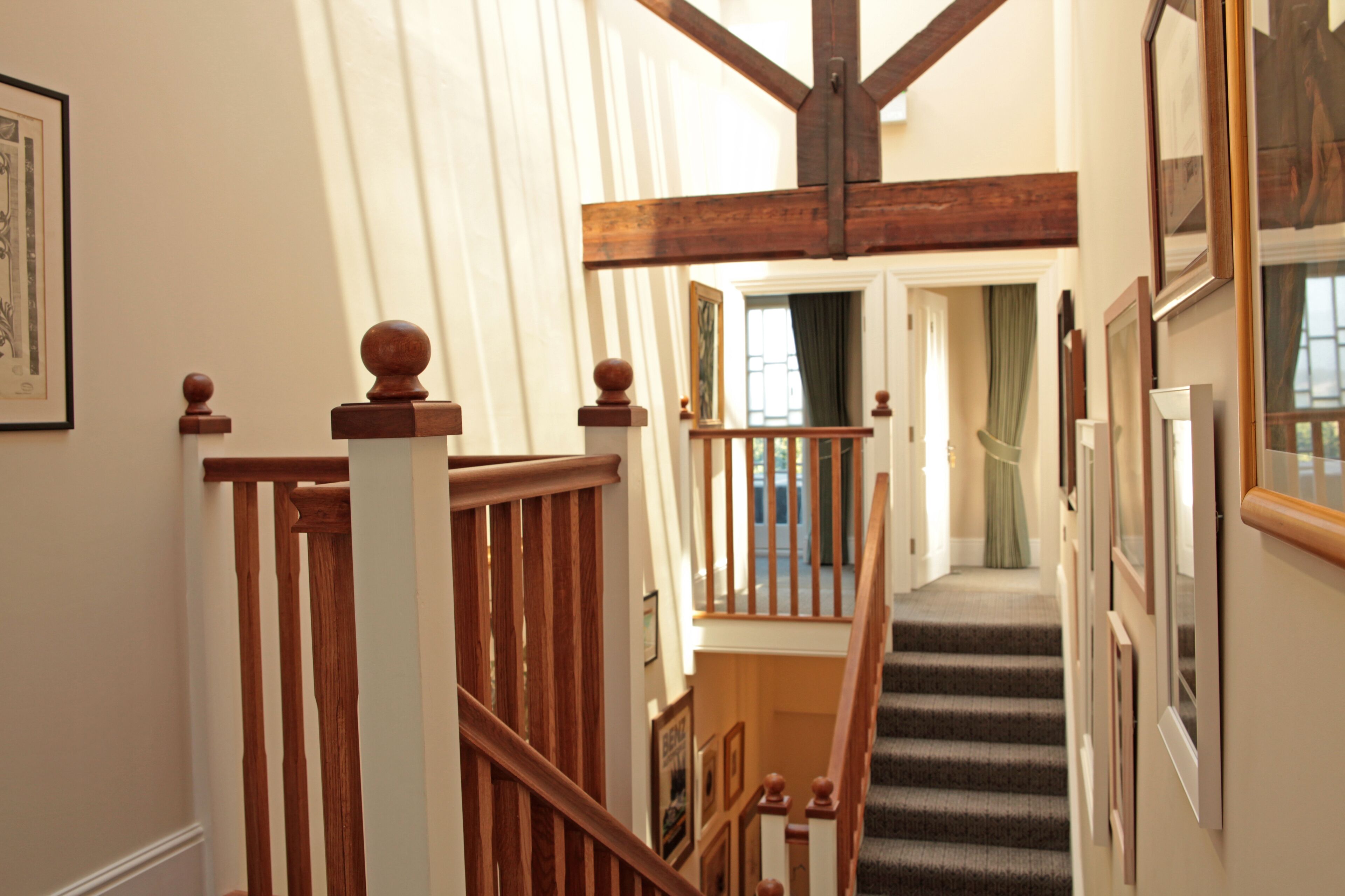 A staircase with wooden balusters and a handrail, leading to a landing with a view of a room.