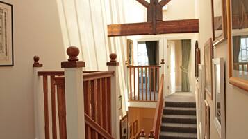 A staircase with wooden balusters and a handrail, leading to a landing with a view of a room.