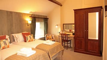 A hotel room with two beds, a desk, a chair, and a wardrobe.