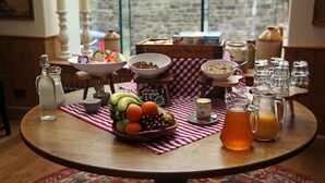 A breakfast table with a bowl of fruit, cereal, and a pitcher of orange juice. - Y Capel (Conwy)