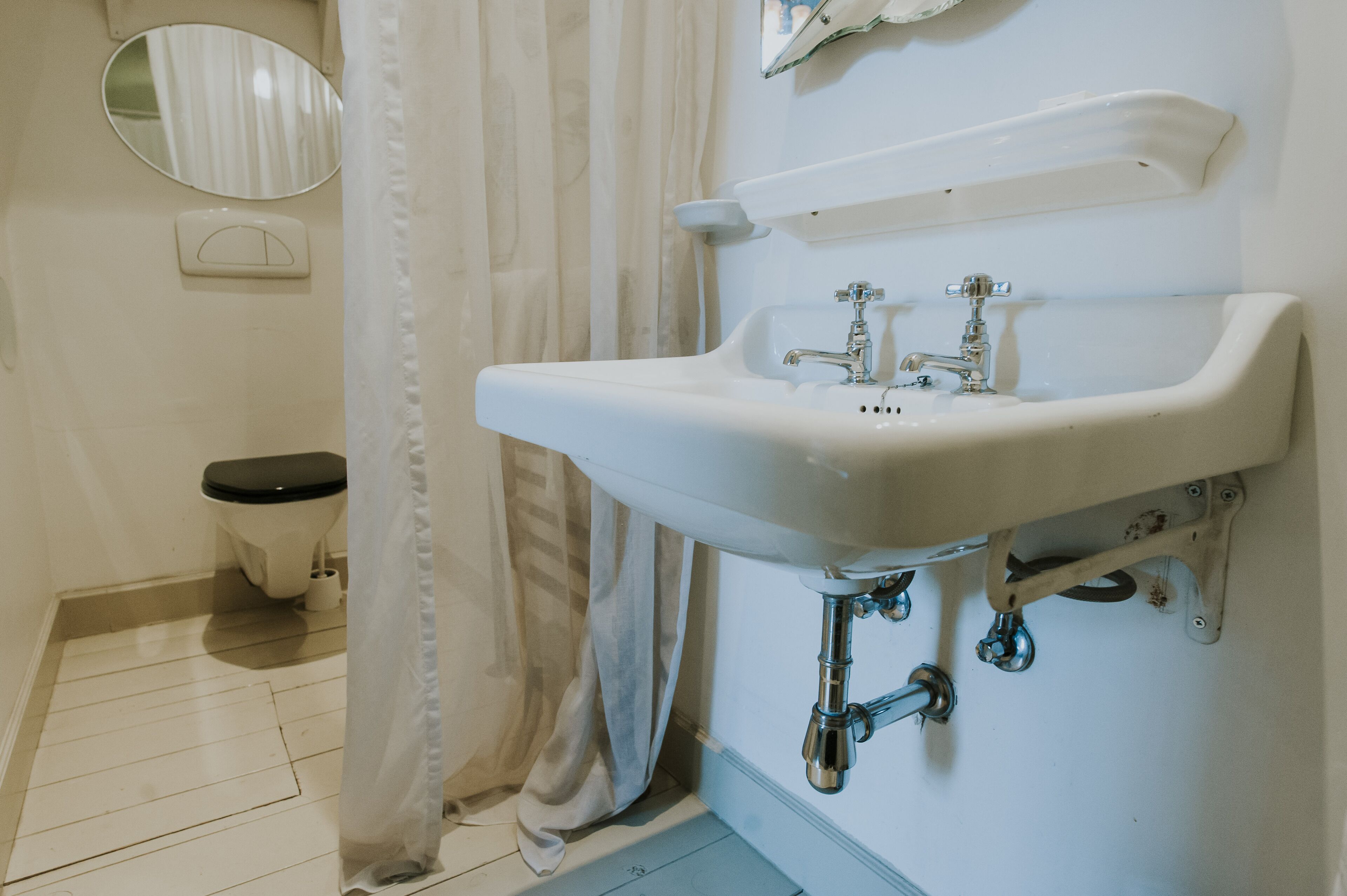 Un bagno con lavandino bianco, servizi igienici, uno specchio e una tenda da doccia.