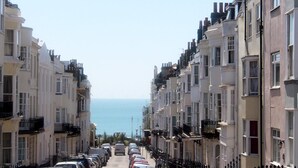 Una calle estrecha bordeada de edificios de varios pisos, cada uno con balcones y vistas al mar.