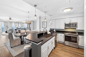 A modern kitchen with a central island, stainless steel appliances, and a dining area with a view.
