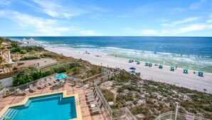 Ein Poolbereich mit Liegestühlen und Sonnenschirmen, ein Strand mit Liegestühlen und Sonnenschirmen sowie Blick auf den Ozean.