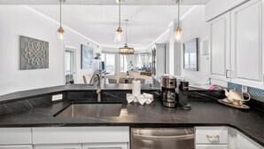 Una cocina moderna con encimera negra, electrodomésticos de acero inoxidable e iluminación colgante.