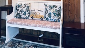A living room with a wooden wall panel, a white sofa with floral cushions, and a painting of a cow.