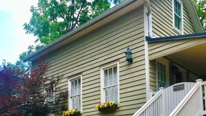 A two-story house with a front porch, a staircase with white railings, and flower boxes on the windows.