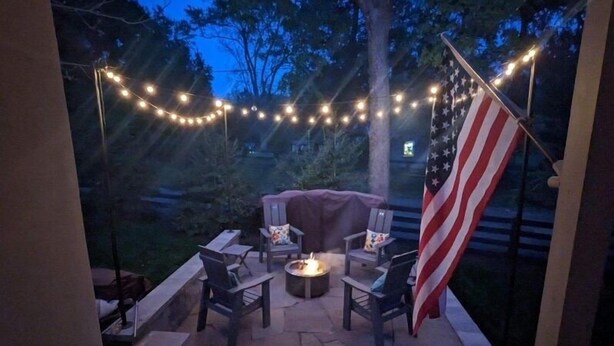 An outdoor patio with a fire pit, seating, and an American flag.