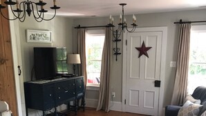 A living room with a sofa, a coffee table, a TV, a dresser, and a chandelier.