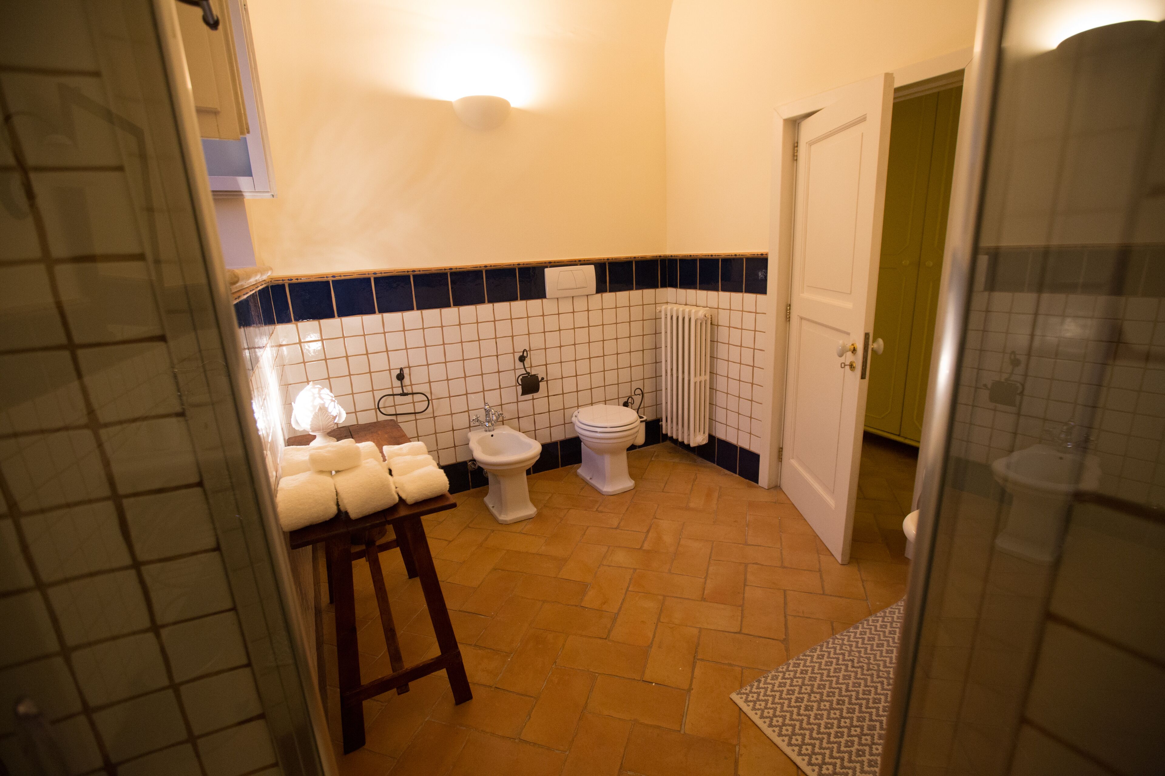 A bathroom with a white toilet, bidet, and a towel rack with towels.