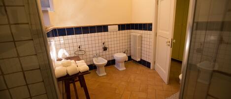A bathroom with a white toilet, bidet, and a towel rack with towels.