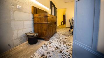 Un pasillo estrecho con un armario de madera, piso de baldosas y una puerta.