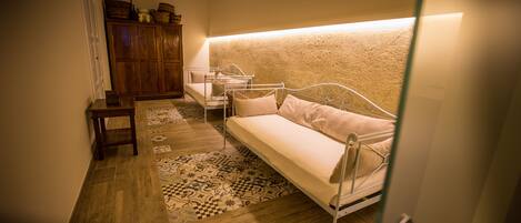 A small, cozy room with a single bed, a wooden cabinet, and a patterned rug.