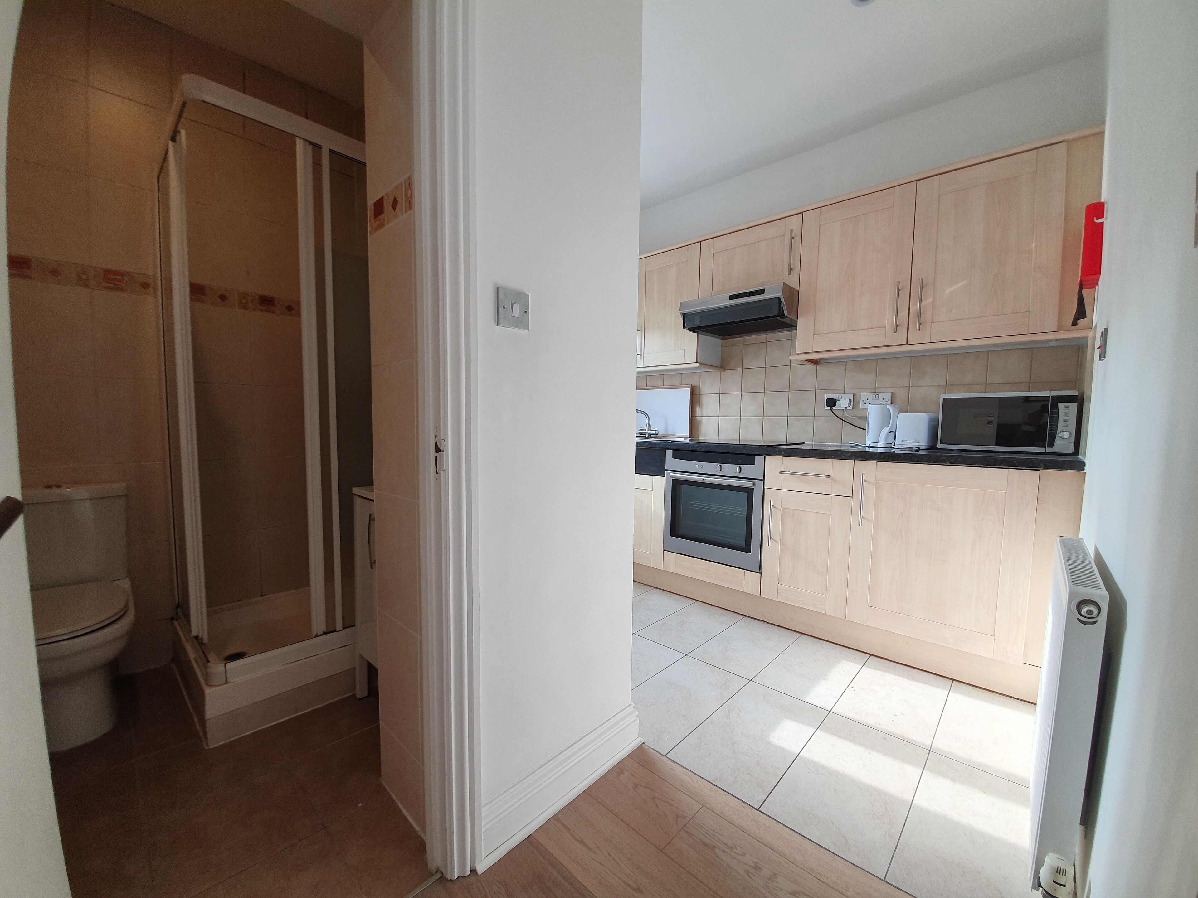 A modern kitchen with wooden cabinets, a microwave, an oven, and a sink.