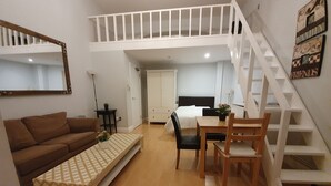 Un espace de vie compact comprenant une chambre en mezzanine, un coin repas et un canapé.