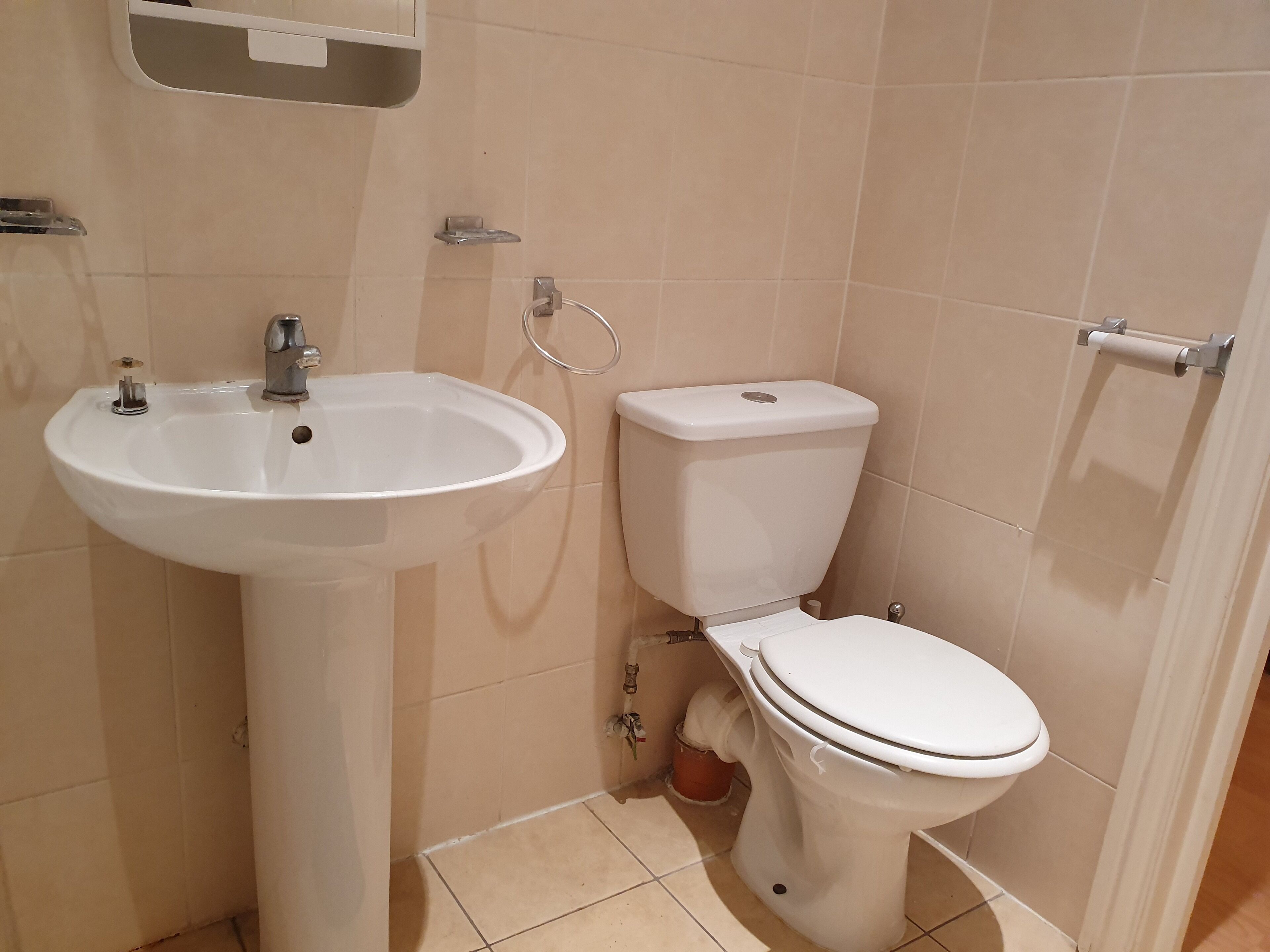 A bathroom with a white sink, toilet, and a towel rack.