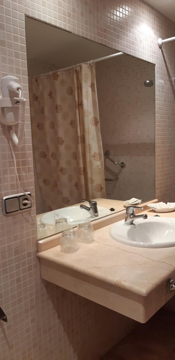 Un baño con lavamanos doble, un espejo grande y zona de ducha.