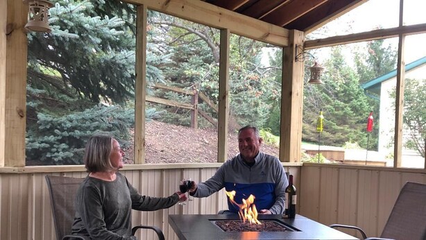 Un patio al aire libre con una chimenea, cubierta de madera y vistas a árboles.