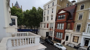 A street view with buildings, a road, and parked cars. - Studio Apartment in South Kensington 16 (London)
