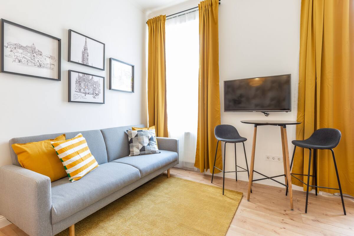 A living room with a sofa, two chairs, a TV, and framed pictures on the wall.
