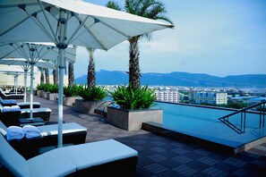 Una piscina al aire libre, sombrillas, sillones reclinables de piscina