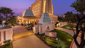 Un hôtel moderne doté d’une tour imposante, d’une entrée bien éclairée et d’un jardin aménagé.