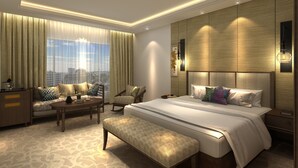 Une chambre d’hôtel moderne avec un grand lit, un canapé, une table basse et un banc.