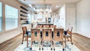 A spacious kitchen with a central island, wooden dining table, and chairs.