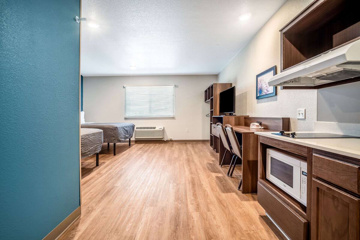 A compact kitchenette with a microwave, stove, and ventilation hood. There is a dining area with a table and chairs.