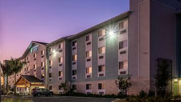 A multi-story hotel with a prominent sign, a parking lot, and a well-lit entrance.