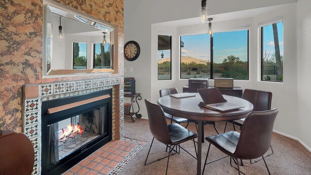 A dining area with a fireplace, large windows, and a view of the outdoors. - Upscale Private Home In A Quite Gated Community With Breathtaking Mountain Views (Tucson)
