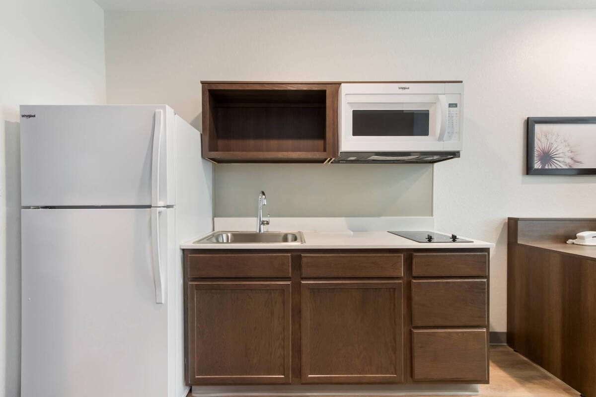 A kitchen with a white refrigerator, a microwave, and wooden cabinets.