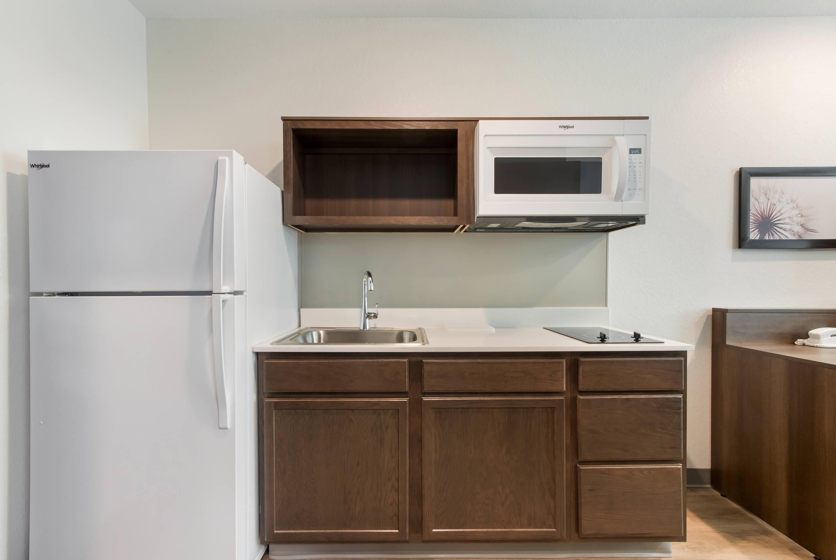 Una cocina compacta con un refrigerador blanco, un microondas y armarios de madera.