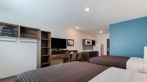 A hotel room with two beds, a desk with a chair, a television, and a microwave. - WoodSpring Suites Tamarac (Tamarac)